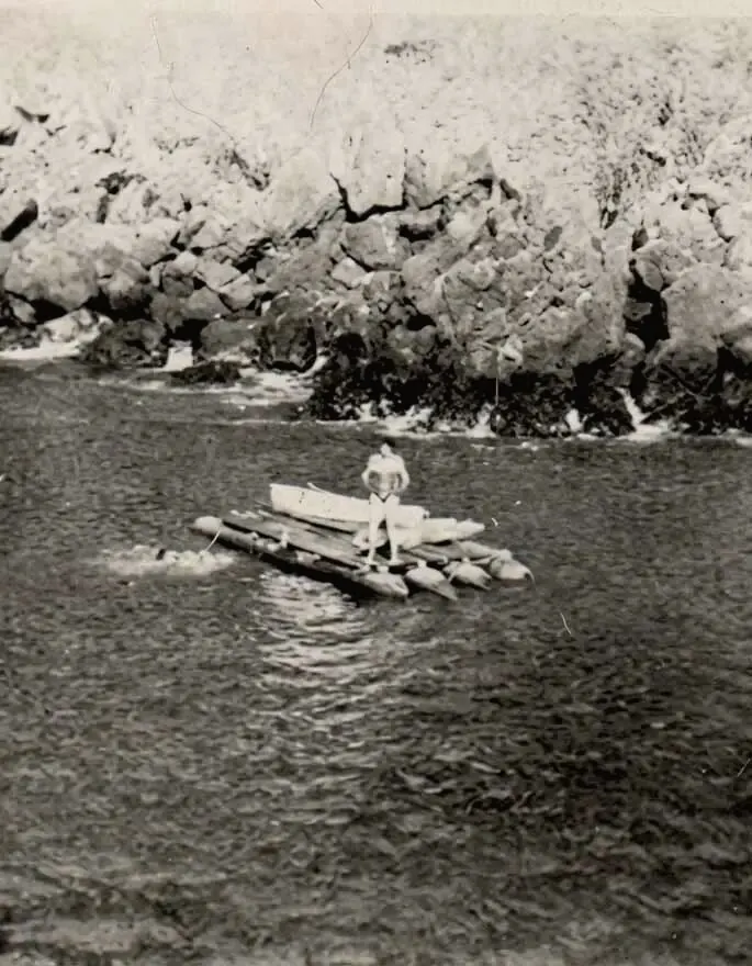 Fotografía antigua de Luis Jácome sobre una balsa junto a un acantilado